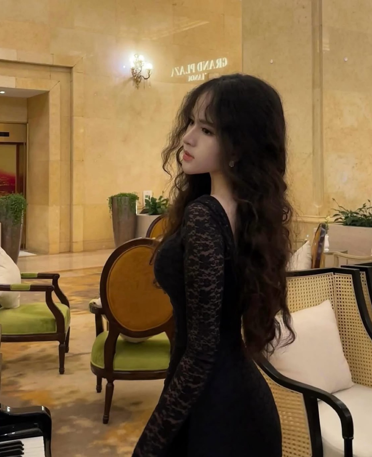 Clara in a black lace dress beside a piano