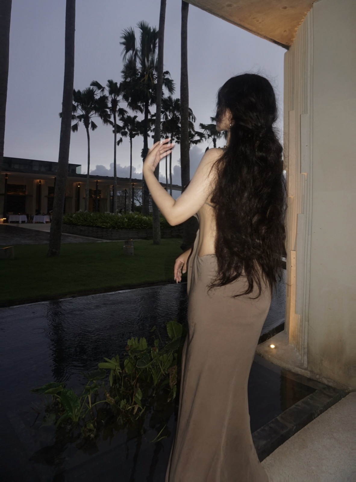 Clara beside palm trees at dusk